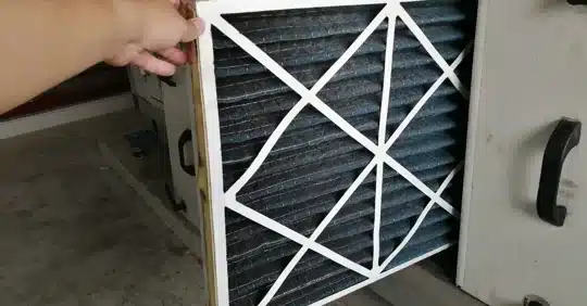 Hands replacing a dirty HVAC air filter with a clean one